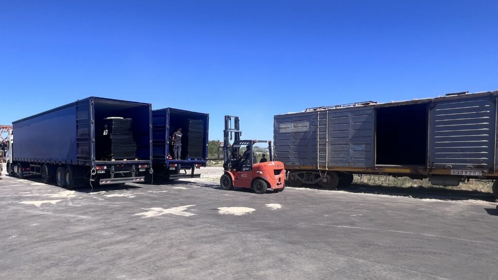 Operación de transbordo de carga desde camión a tren mediante autoelevador en esquema logístico multimodal.