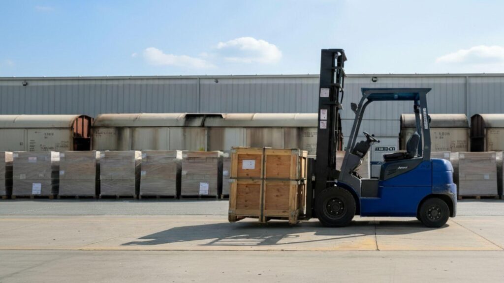 Transbordo de mercadería entre camión y tren mediante autoelevador en operación logística multimodal.